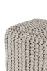 Close-up view of a beige cube-shaped pouf showcasing intricate woven knit detailing, ideal for adding texture to living spaces.