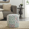 Round pouf with colorful floral patchwork design placed in a cozy living room setting with neutral-toned furniture and decor elements.