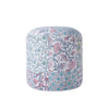 Round pouf with colorful floral and leaf patchwork design, featuring vibrant patterns in red, blue, yellow, and green on a white base.