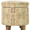 Round storage ottoman with a vintage-inspired multicolor pattern, sturdy wooden legs, ideal for seating or storage in living spaces.