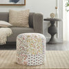 Round pouf with a colorful floral patchwork design, featuring vibrant patterns and a cozy living room setup with a beige sofa.