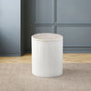 Cylindrical white table with a marble top, set against a modern blue-paneled wall, showcasing its elegant and minimal design.