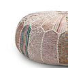 Close-up of a round pouf showcasing detailed patchwork in pink, beige, and teal with decorative stitching and soft textures.