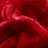 Close-up view of the embossed floral texture on the burgundy plush blanket, showcasing intricate detailing and softness.
