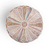 Top-down view of a round pouf with intricate patchwork design in shades of pink, beige, and teal, featuring decorative stitching.