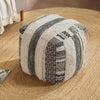 Square pouf with black and white textured patterns and stripes, set on a round jute rug in a cozy living room environment.