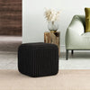 Black knitted cotton cube pouf placed in a modern living room, ideal for seating or decoration, complementing stylish interiors.