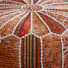 Detailed close-up of a vibrant patchwork pouf with orange, red, and brown hues, featuring intricate patterns and white stitched accents.