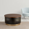 Round coffee table featuring a dark ribbed base, wooden top, and gold metal base accent, placed in a modern living room setting.