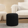 Albany Living cylindrical knitted pouf in black, placed on brown rug with white sofa in background, suitable for contemporary home decor.