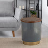 Stylish cylindrical side table with a gray textured body, gold metal base, and wooden top, placed beside a gray sofa in a modern room.