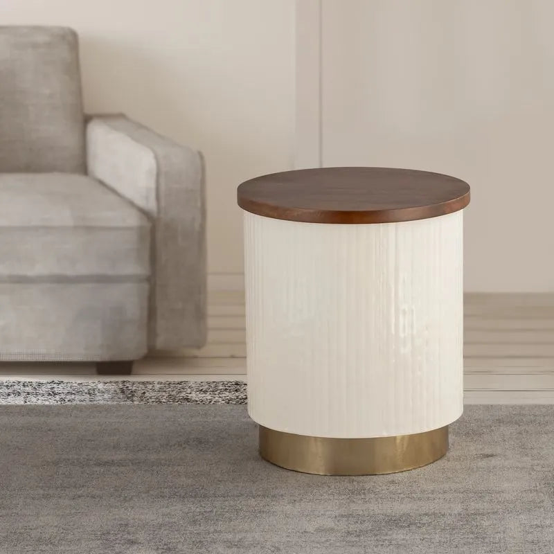 Elegant white cylindrical side table with a wooden top and gold base, placed next to a beige sofa in a cozy modern living space