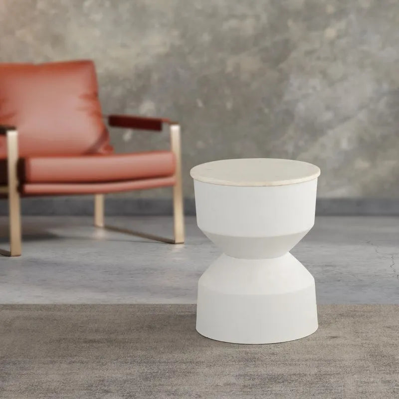 A white modern drink table placed in a room with a red chair and gray walls, showcasing its aesthetic design.