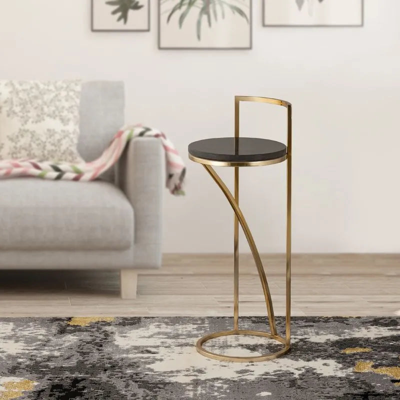 Elegant gold-framed round table with a black marble top placed beside a gray sofa, creating a stylish and modern living space.