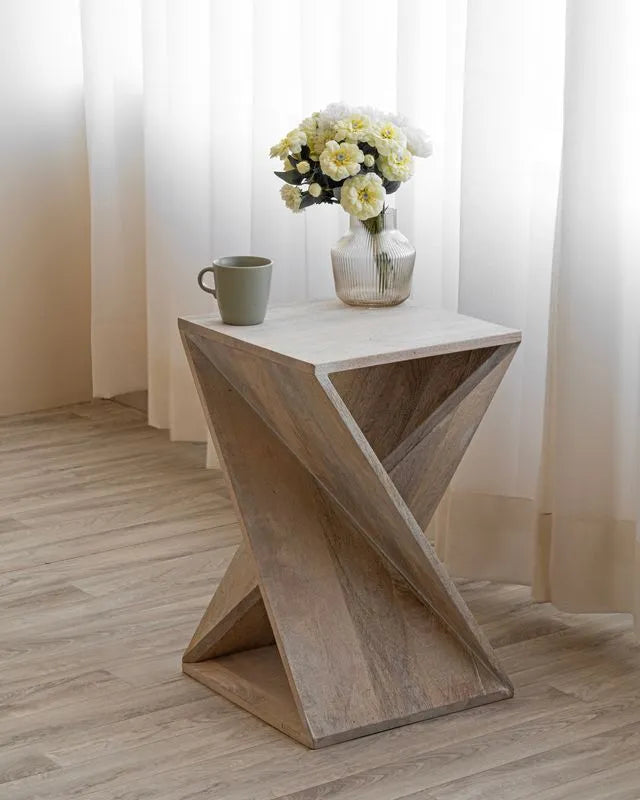 Whitewashed twisted wood end table with a unique geometric design, topped with a vase of yellow flowers and a green mug, adding rustic charm to interiors.