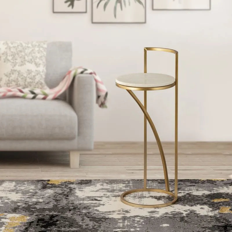 Gold-framed round side table with a marble top, elegantly placed beside a sofa in a modern living room with decor accents.