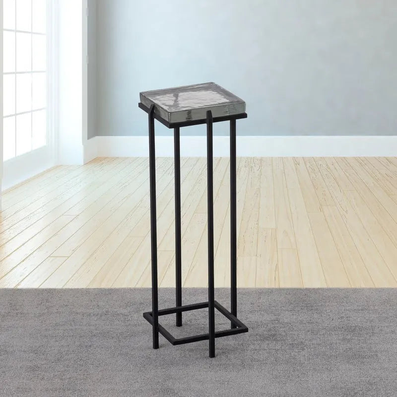 Albany Living T505 Square Casted Glass Drink Table in Clear finish, with a black metal frame and a reflective clear glass top, positioned on a soft gray rug with natural light from a nearby window.