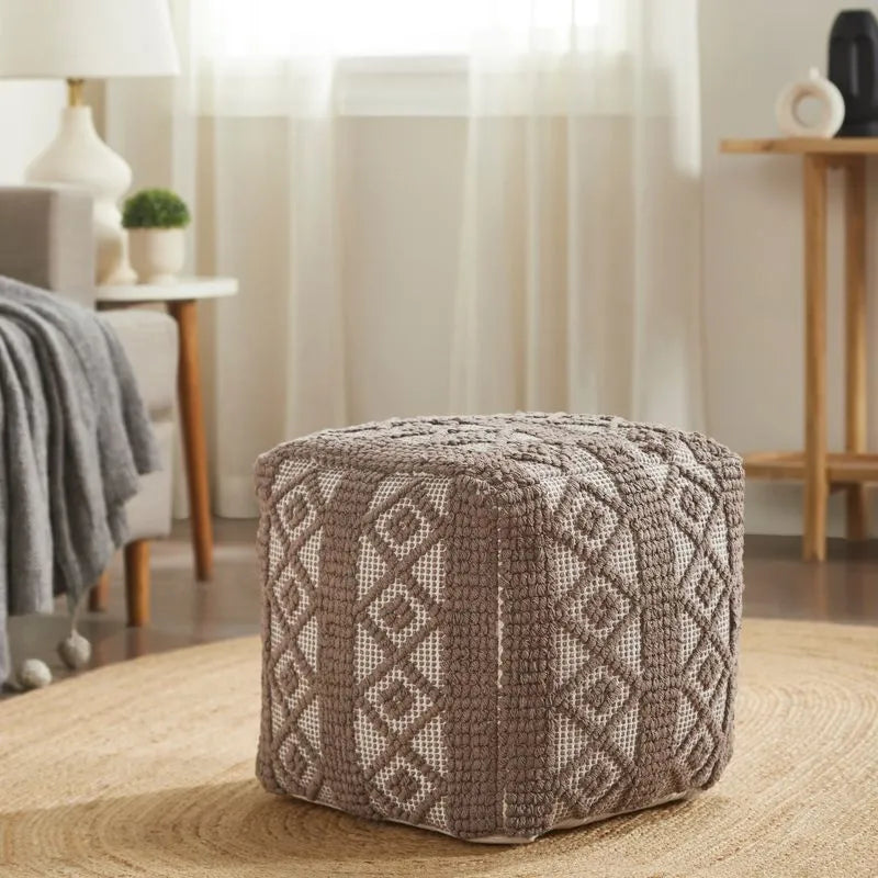 Brown diamond square pouf with diamond patterns, handwoven texture, placed on a round natural fiber rug in a cozy living room.