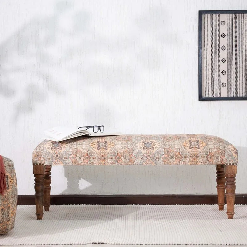 Brown upholstered bench with ethnic patterns, sturdy wooden legs, and an open book on top, perfect for enhancing living room decor.