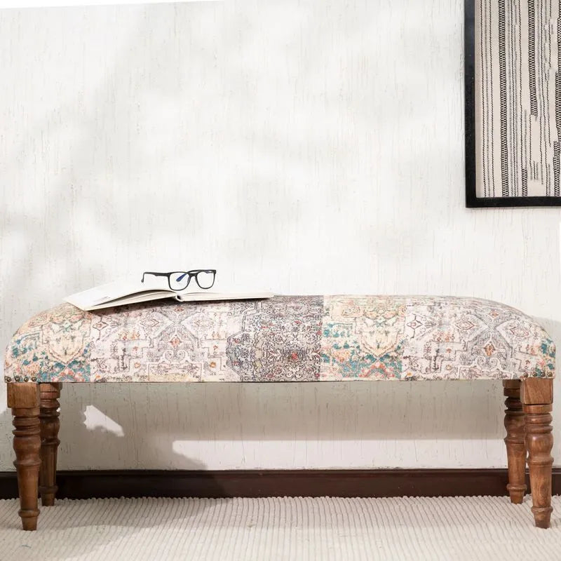 Beige upholstered bench with ethnic-inspired patterns, sturdy wooden legs, and an open book, adding style and function to any decor.